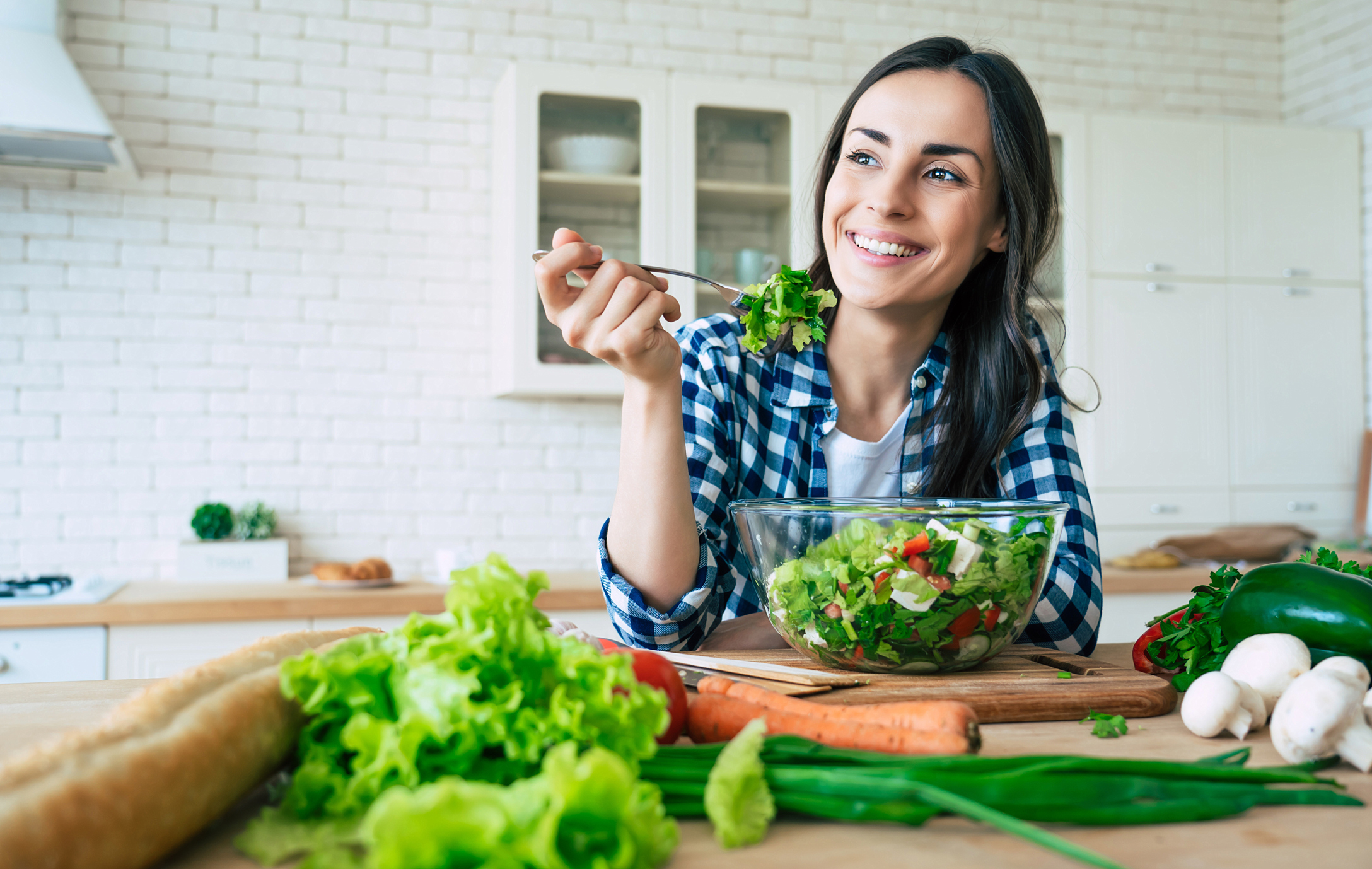Estilo de vida saludable. Buena vida. Alimentos orgánicos. Verduras. Retrato de primer plano de una joven feliz mientras prueba una ensalada sabrosa vegana en la cocina de su casa.