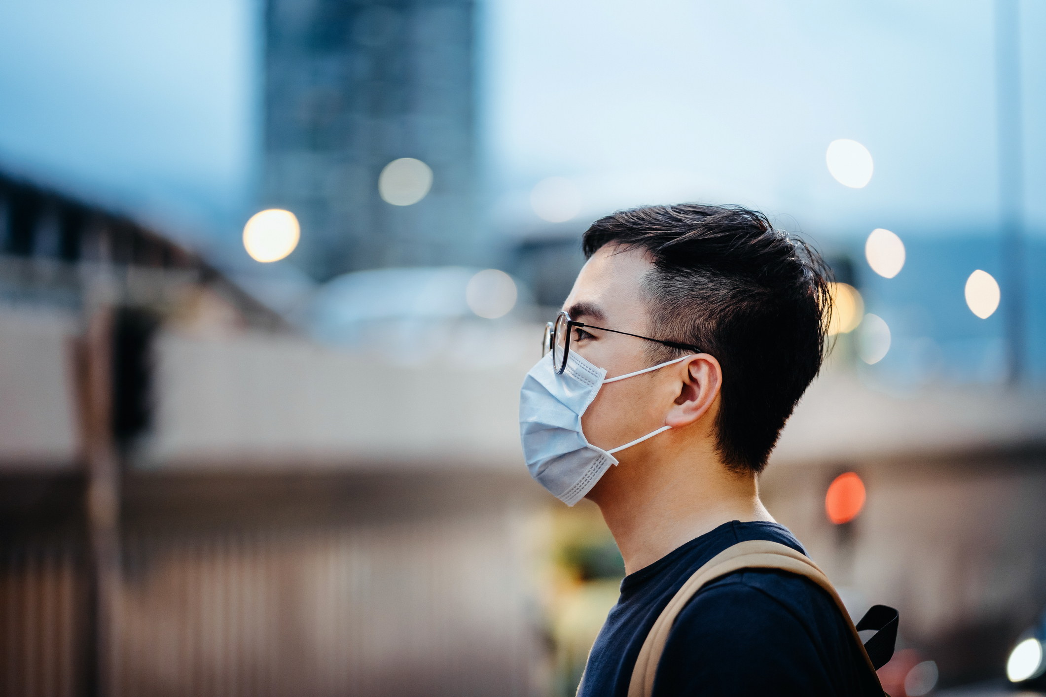 Retrato de un joven asiático con mascarilla para protegerse y prevenir la propagación de virus en la ciudad