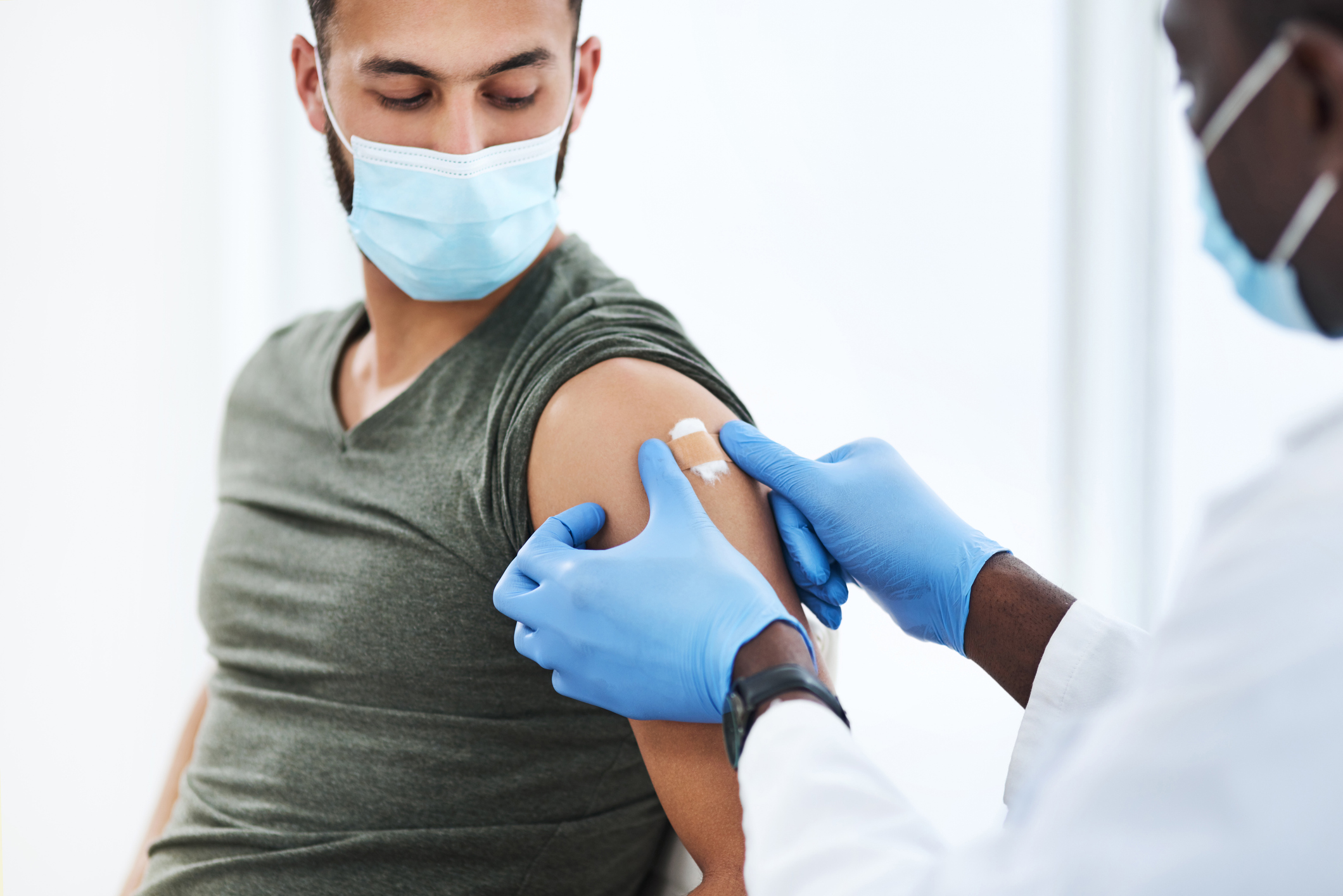 Imagen de un médico colocando un apósito después de inyectar a un paciente en su brazo durante una consulta en una clínica