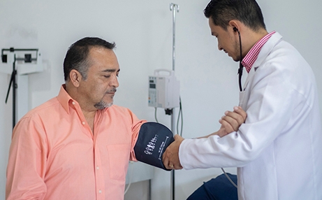 Médico masculino con paciente masculino que toma la presión arterial en el consultorio del cardiólogo 