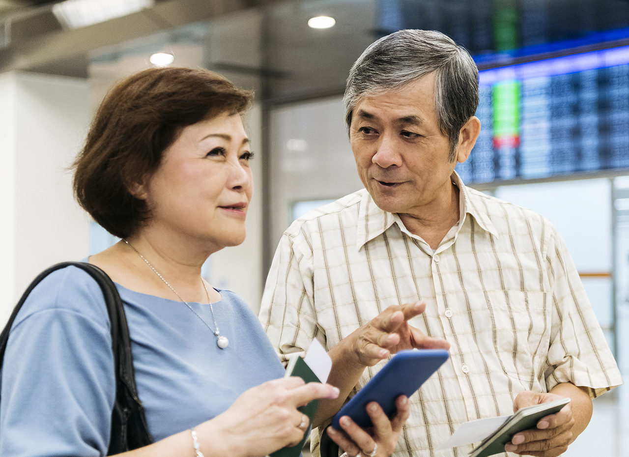 Adultos mayores activos en el aeropuerto utilizando una aplicación móvil para controlar la diabetes mientras viajan
