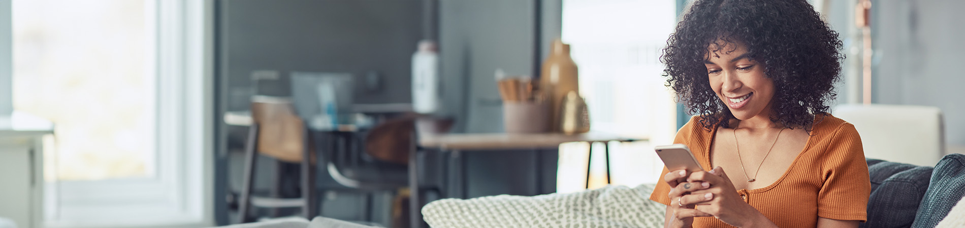 mujer sonriente usando un dispositivo móvil en casa