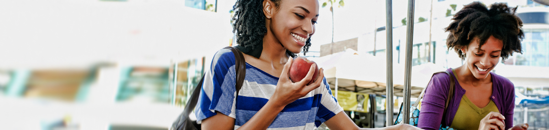 dos mujeres caminando, una de ellas come una manzana